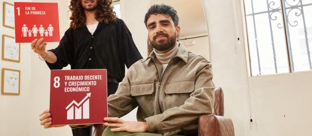 Two men hold SDG signs 1 and 8